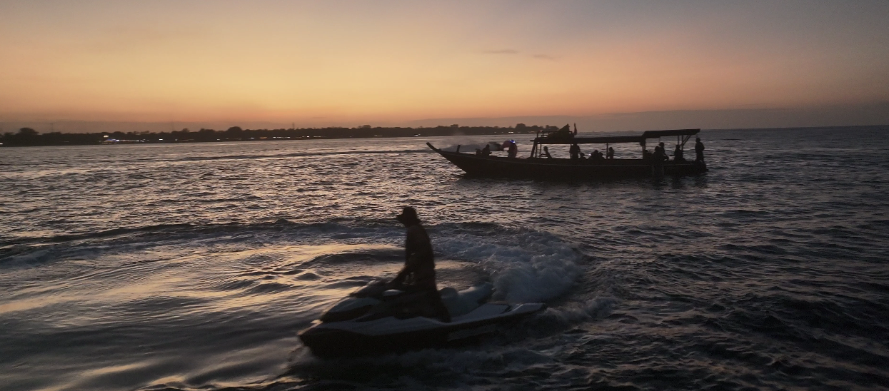 Guests riding a jet ski beside the Jasper boat at dusk