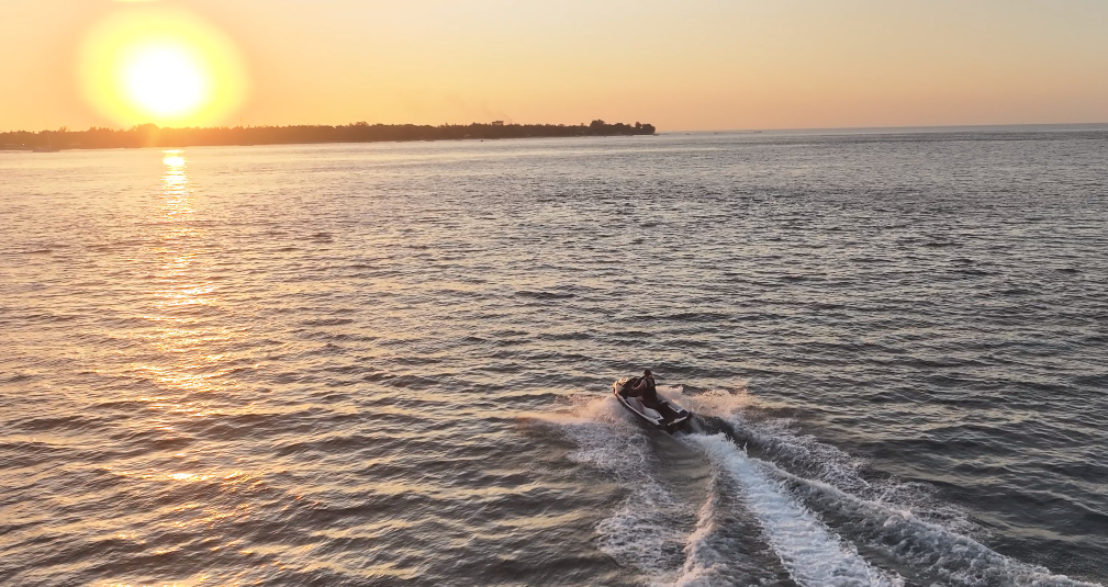 Jet ski carving across the water in front of the boat at sunset